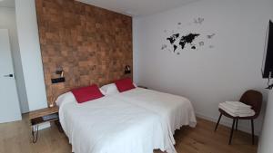 a bedroom with a white bed and a brick wall at Casa Huidobro Valle II in Sardón de los Frailes