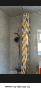 a bathroom with a shower with a yellow and white shower curtain at Conner house in Middlesbrough +11 photos