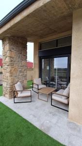 a patio with lounge chairs and a stone wall at Casa Huidobro Valle II in Sardón de los Frailes