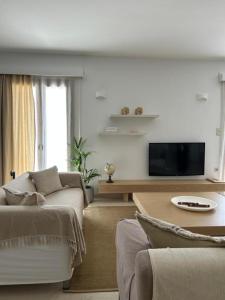 a living room with a couch and a tv at Villa Elia in Mélanes