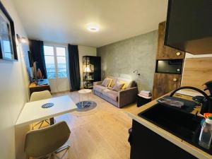 a kitchen and living room with a couch and a table at Le Chaplin face au lac Léman in Évian-les-Bains