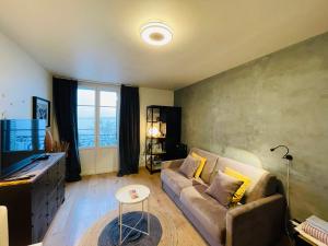 a living room with a couch and a large window at Le Chaplin face au lac Léman in Évian-les-Bains