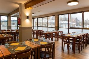 a restaurant with wooden tables and chairs and windows at Hotel Encamp by Nexta in Encamp