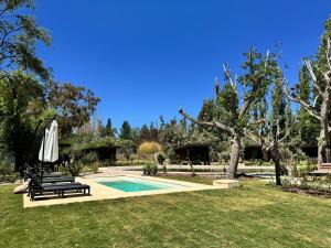a pool with two chairs and an umbrella in a yard at LÜN Lodges in Chacras de Coria