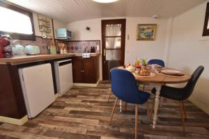 a kitchen with a table and blue chairs in a room at Péniche Le Makara in Avignon