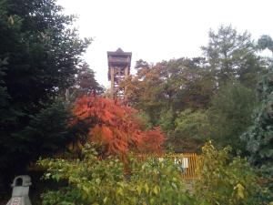 a clock tower in the middle of a garden at Rita Vend&eacute;gszob&aacute;k in Sopron