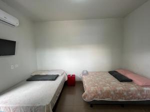 two twin beds in a room with a tv at Residencial Jasmim quarto Standard 01 in Palmas
