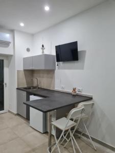 a kitchen with a black counter and two white chairs at Le 2TORRI in Falconara Marittima
