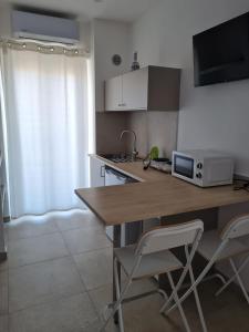 a kitchen with a counter with two chairs and a microwave at Le 2TORRI in Falconara Marittima +3 photos
