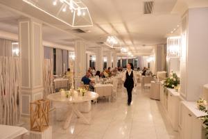 a woman walking through a restaurant with tables and chairs at Riviera Hotel in Senigallia