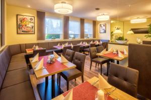 a restaurant with wooden tables and chairs and windows at HRC Pfeffermühle in Landstuhl