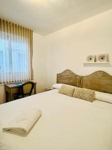 a bedroom with a white bed with a wooden headboard and a window at El Rincón Azul Benicasim centro in Benicàssim