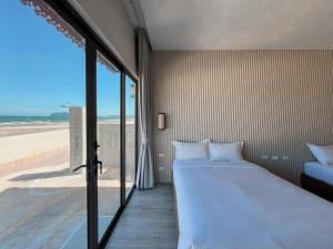 a bedroom with a bed and a view of the beach at Cape and Sea Resort in Ban Boet