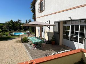 a patio with a table and an umbrella next to a building at Gîte Villa Santina in Piquecos