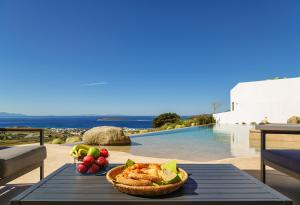 a table with a bowl of fruit and a basket of food at Skylines Estate Paros in Kampos Paros