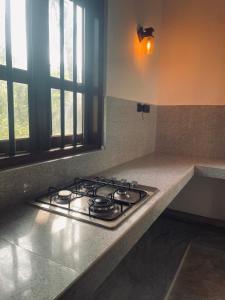 a stove top in a kitchen next to a window at RailNest in Talpe