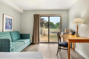 a living room with a couch and a desk with a table at Rodeway Inn in Saint John