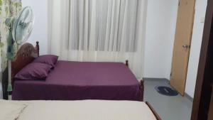 a bedroom with a purple bed and a fan at Thoughtfully Updated 1960s Jaffna House in Jaffna