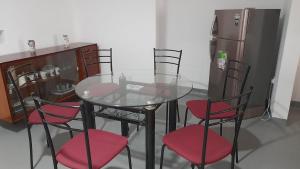 a glass table with four chairs and a refrigerator at Thoughtfully Updated 1960s Jaffna House in Jaffna
