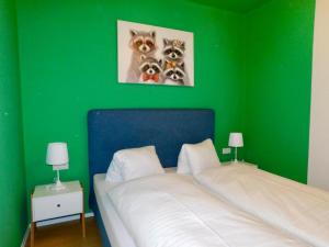 a green bedroom with a bed with two pictures of cats at OhneTamTam in Ehrenhausen +1 photo