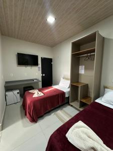 a hotel room with two beds and a flat screen tv at Suítes Vivence Hotel in Goianésia