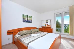 a white bedroom with a large bed and two windows at Apartment Tina Split in Split