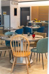 a dining room with tables and chairs in a restaurant at Logis Hôtel Alizéa Le Mans Nord in Saint-Saturnin