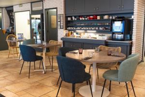 a restaurant with two tables and chairs and a counter at Logis Hôtel Alizéa Le Mans Nord in Saint-Saturnin
