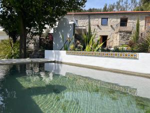 a swimming pool with a fountain in front of a house at Quinta da Lembrança in Arcos de Valdevez