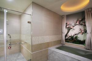 un bagno con doccia e vasca da bagno di Chuang-Tang Spring SPA Hotel - Deyang a Jiaoxi