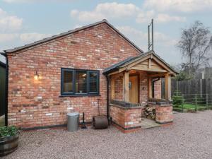 a small brick house with a fireplace in a yard at Otter's Rest in Droitwich