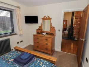 a bedroom with a bed and a dresser with a mirror at Otter's Rest in Droitwich