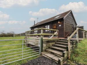 a wooden house with a fence next to a gate at The Barn on The Lagoon in Droitwich
