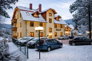 a building with cars parked in the snow at WILLA PETRUS - CENTRUM BALKONY WINDA ŚNIADANIA RELAKS I WYGODa in Karpacz