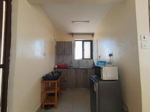 a small kitchen with a refrigerator and a microwave at Modern Nest Studio Kikuyu in Rungiri