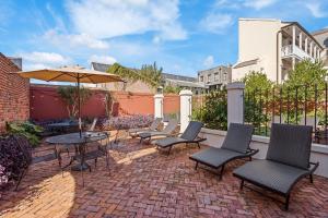 a patio with chairs and a table and an umbrella at Grenoble House in New Orleans