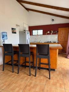 a kitchen with three chairs and a counter with a refrigerator at Manu Kehu in Hanga Roa
