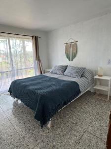 a bedroom with a bed with a blue blanket on it at Manu Kehu in Hanga Roa
