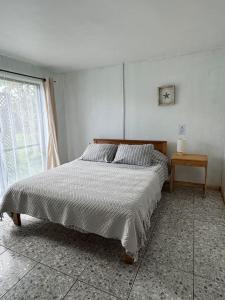 a white bedroom with a bed and a window at Manu Kehu in Hanga Roa +1 photo