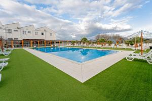 an image of a swimming pool with chairs and grass at Lena Village - Hotel and Spa in Mortágua