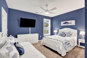 a blue bedroom with two beds and a flat screen tv at Front Porch Lounge in Tybee Island +42 photos