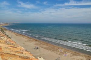 a beach with people on the sand and the ocean at Sea You Apartamentos Valencia Port Saplaya in Port Saplaya