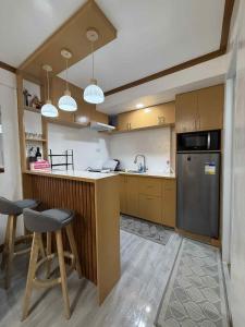a kitchen with wooden cabinets and a counter with stools at JMATS Homestay in Dipolog
