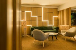 ein Wohnzimmer mit einer Couch, zwei Sesseln und einem Tisch in der Unterkunft HF Fénix Lisboa in Lissabon