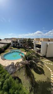 a building with a swimming pool and a palm tree at Apto Areia Branca Canoa Quebrada in Canoa Quebrada