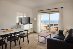 a living room with a table and a couch and a television at Monte Gordo Prestige Apartments in Monte Gordo