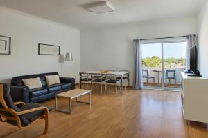 a living room with a couch and a table with chairs at Monte Gordo Prestige Apartments in Monte Gordo