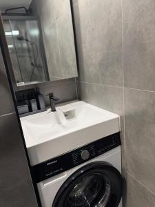 a washing machine with a sink and a mirror at Central Apartment in Jelgava