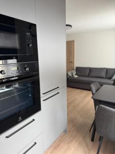 a kitchen with a stove top oven next to a living room at Central Apartment in Jelgava