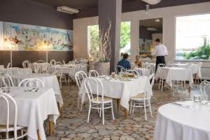 a dining room with white tables and chairs and a waiter at HOTEL TRIONFAL - Fronte Mare - Vicinissimi al Centro in Milano Marittima